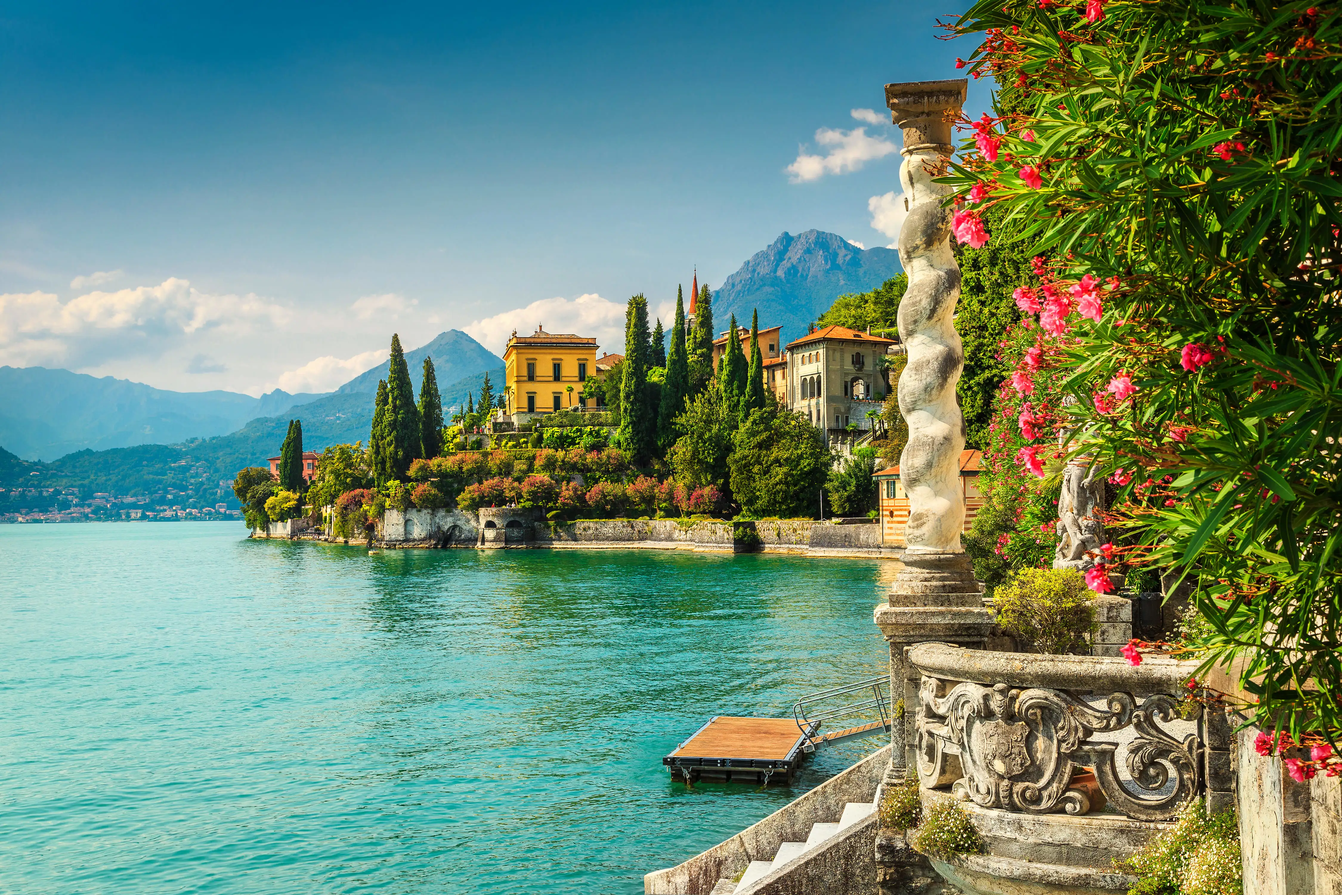 Attractive trees, flowers and stonework line the edges of a beautifully blue lake