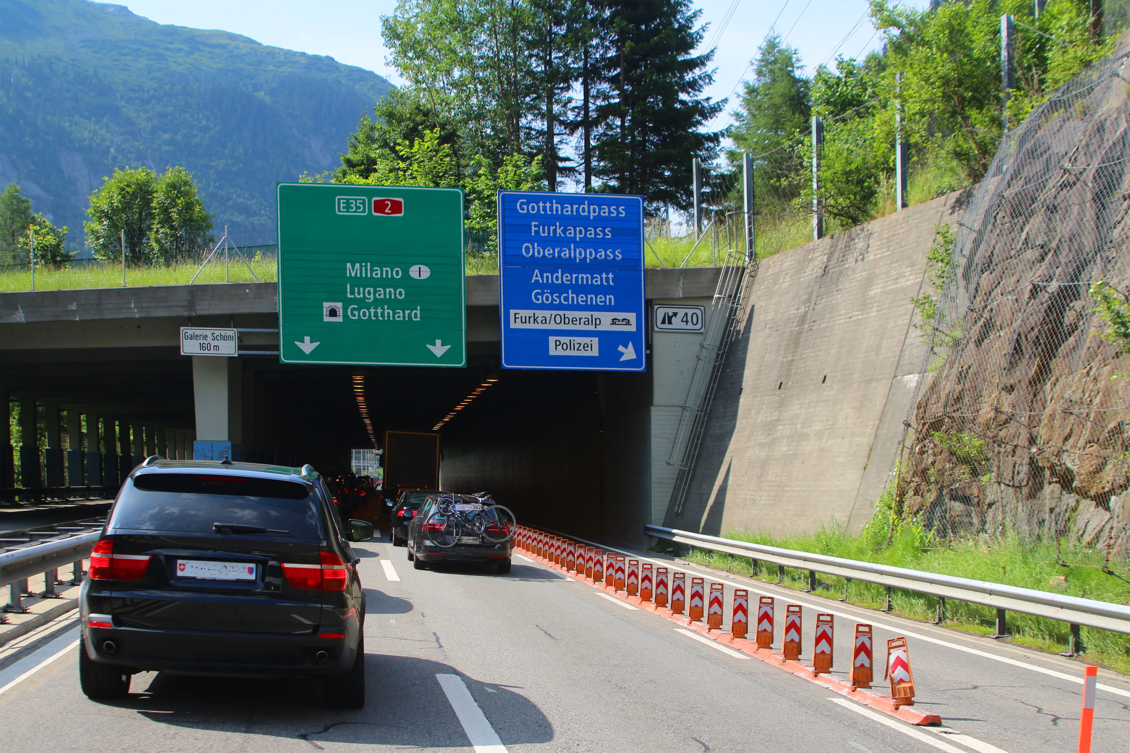 : Overhead road signs with cars approaching a tunnel