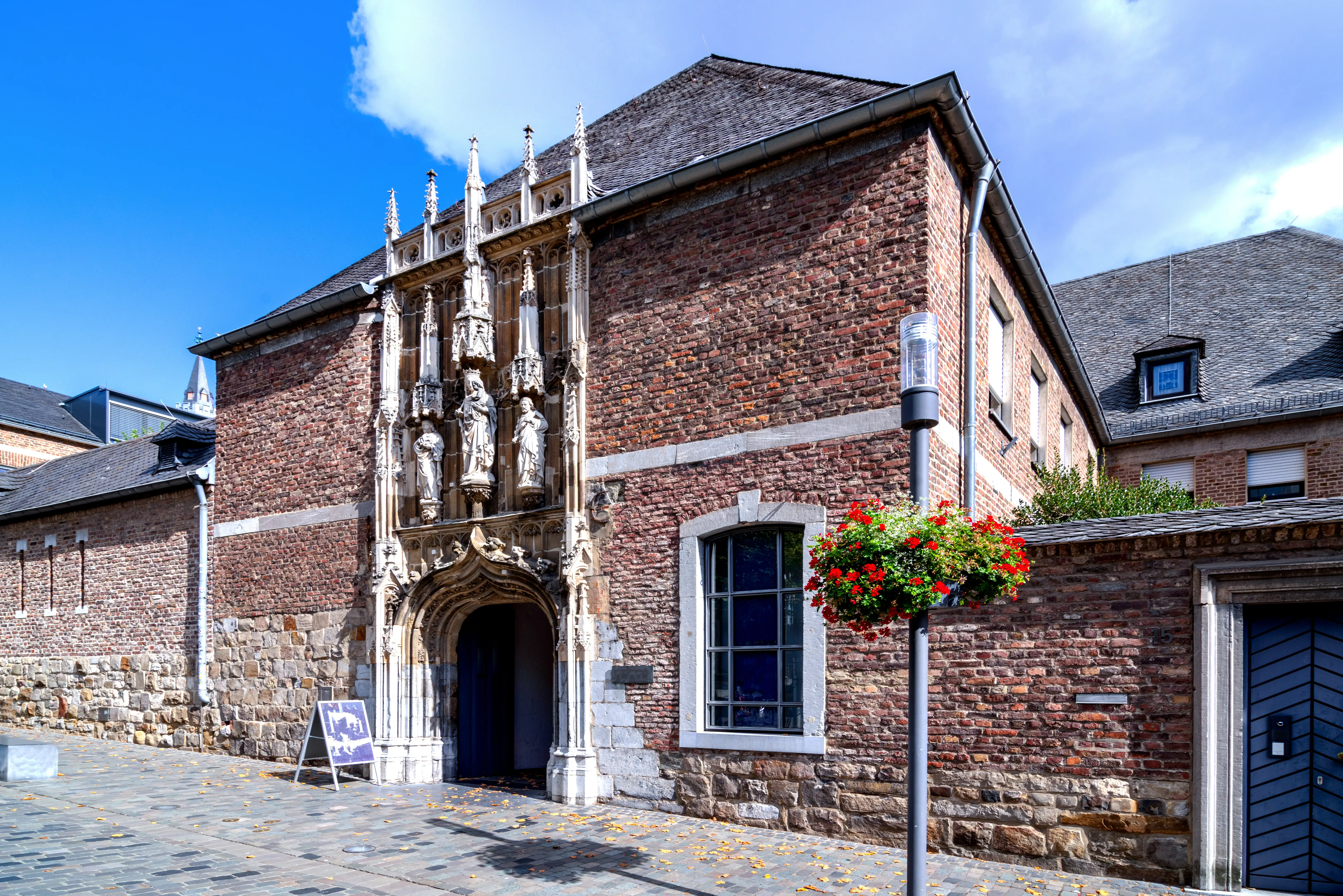 A rather plain 2 storey building with a very intricate, ornate door, with many carved statues above the door