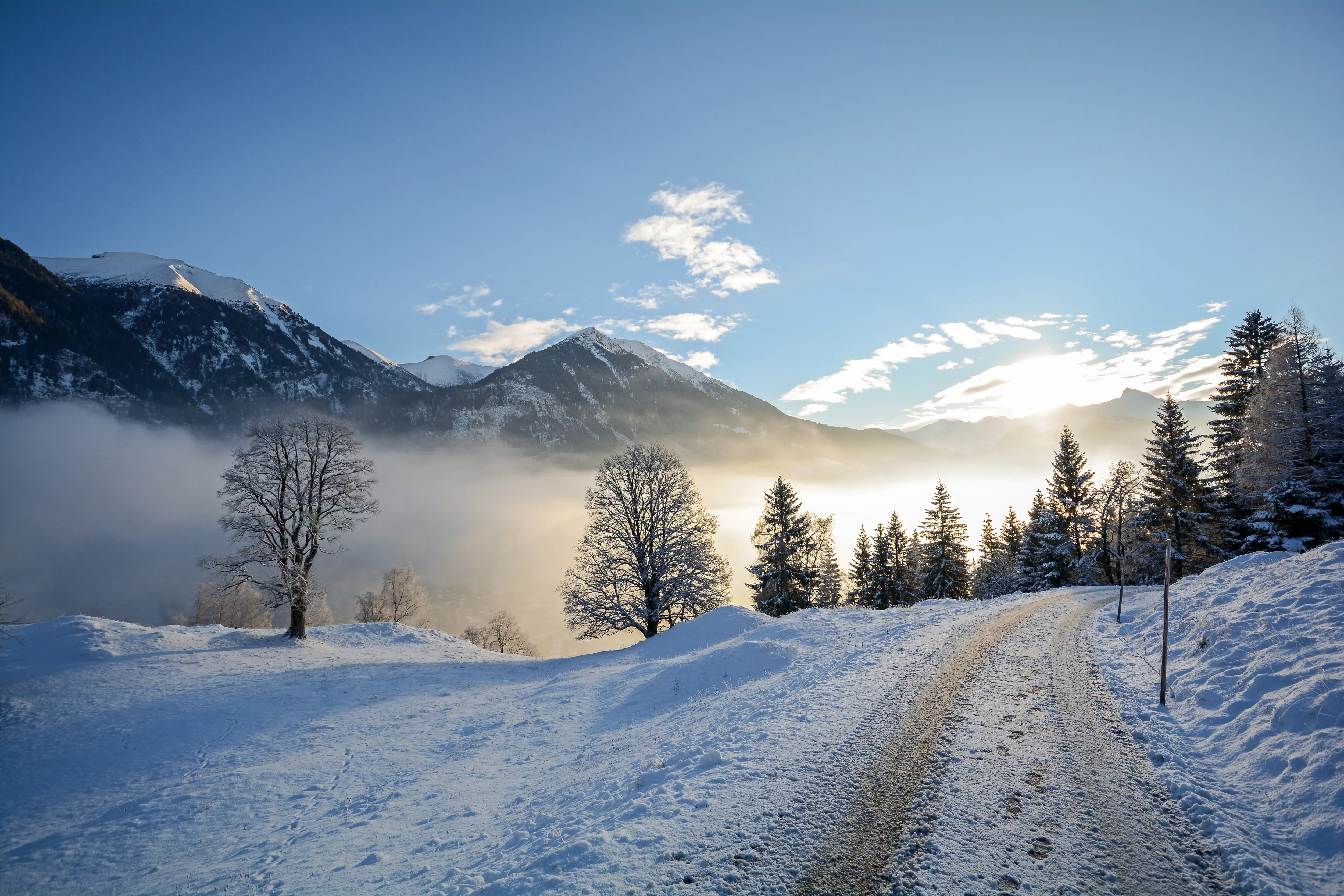 A snow-covered road with a mountain range in the distance