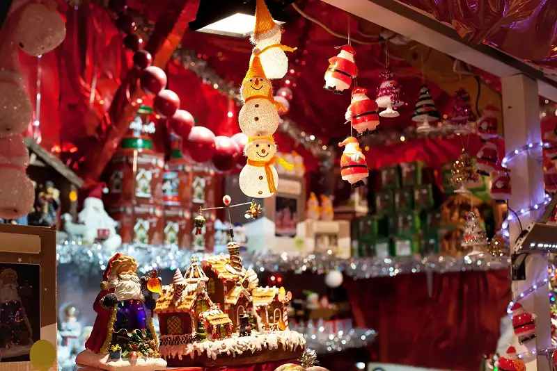 Interior of a decorated Christmas market stall, featuring hanging ornaments, glowing lights and festive decorations.