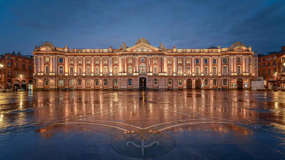 The Place du Capitole in Toulouse at night, illuminated by lights, showcasing the vibrant square in front of the historic building