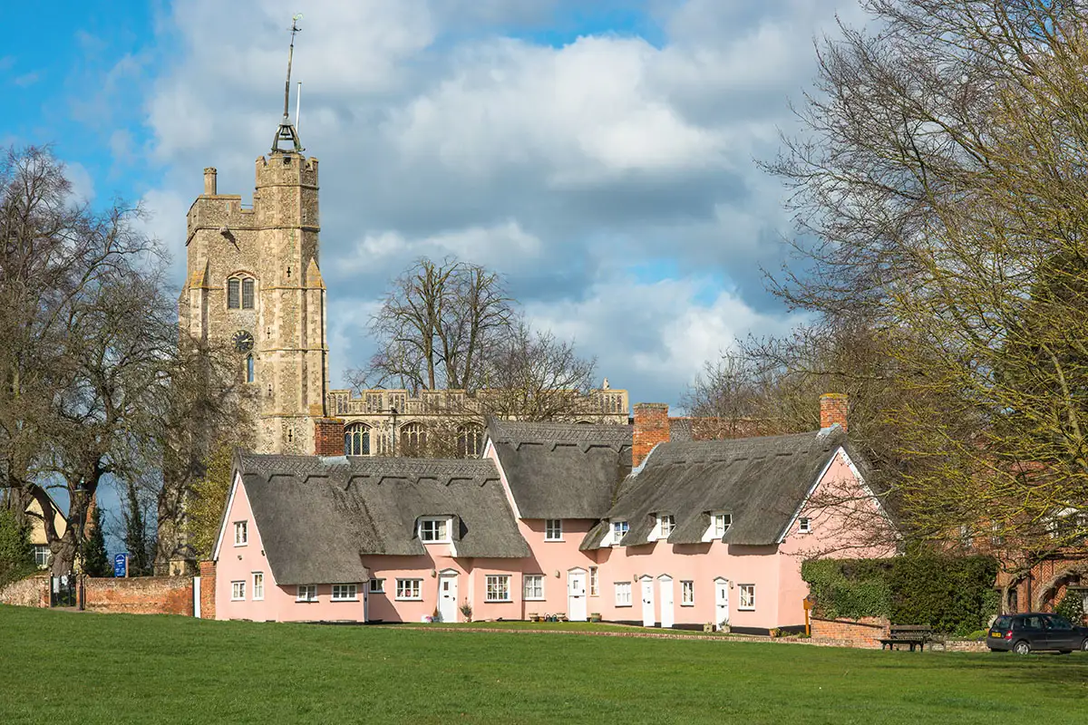 Huizen met rieten daken en middeleeuwse kerk in Cavendish