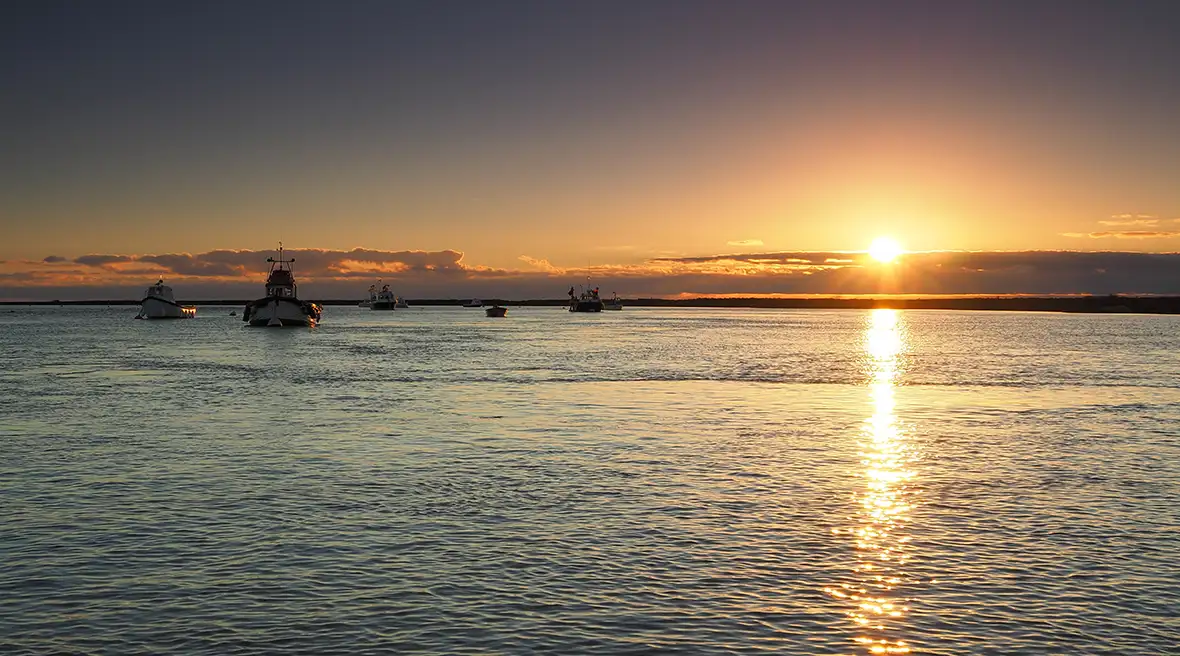 Vissersboten op kalme zee bij zonsondergang