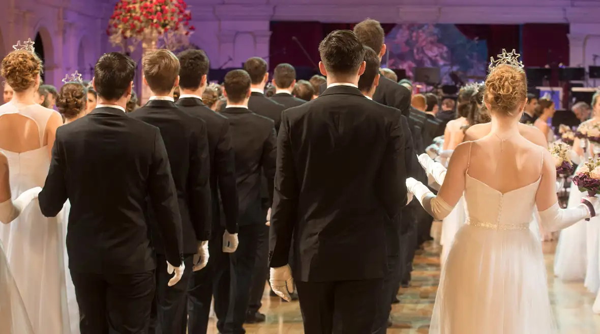 Heren in zwart pak dansen in processie met dames in witte jurk