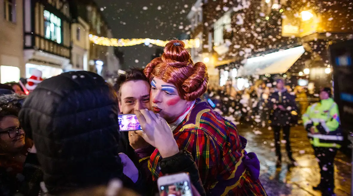 A pantomime dame taking pictures with passers by at the Canterbury Christmas parade