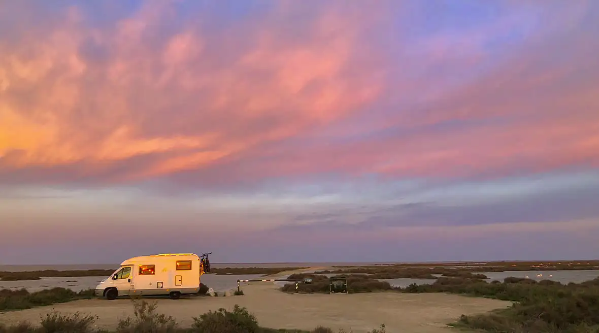 A lone motorhome looks out at a beautiful sunset