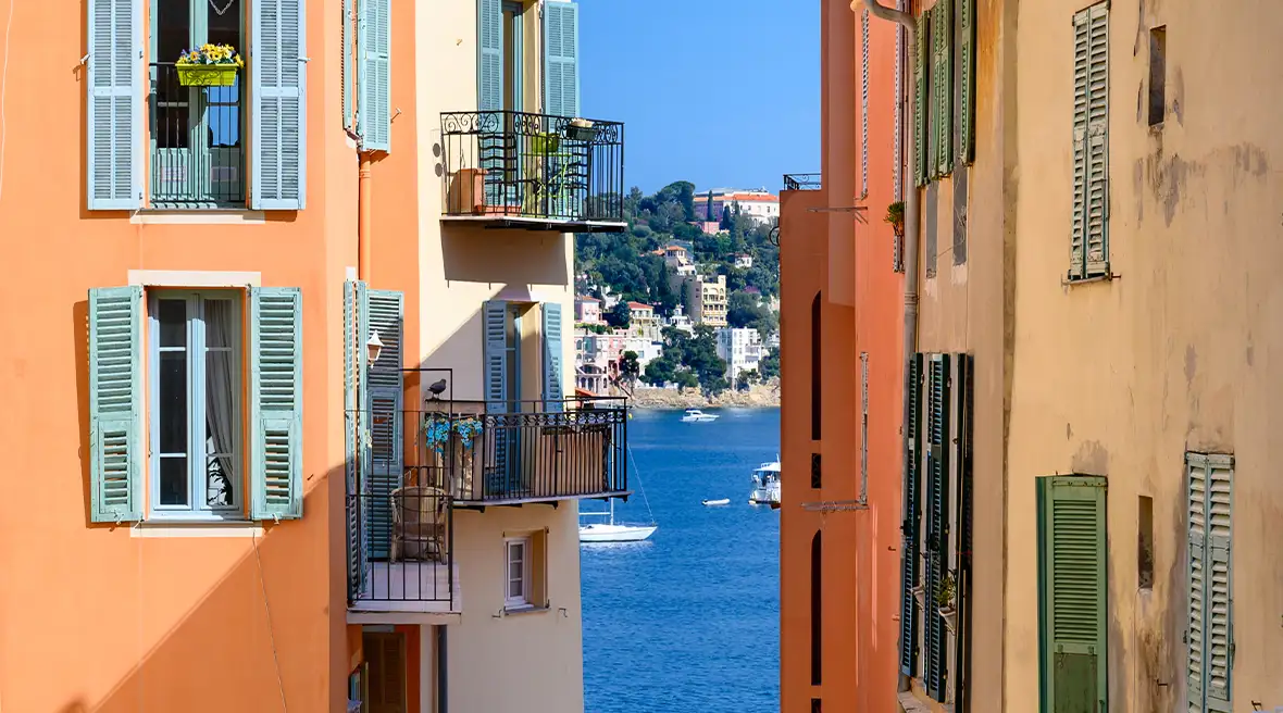 View of old town in Villefranche-sur-Mer with the Mediterranean sea in the background and brightly coloured buildings.