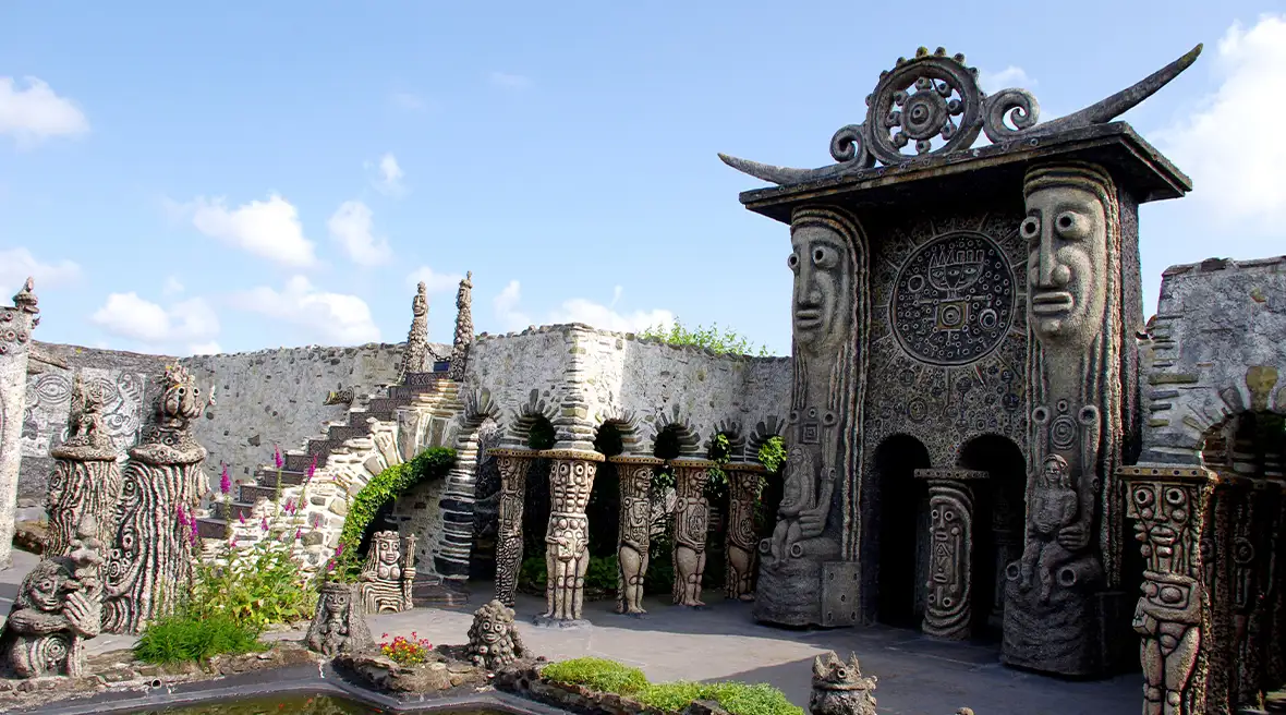 Large temple like structure with faces carved into the stone surrounding a pool of water