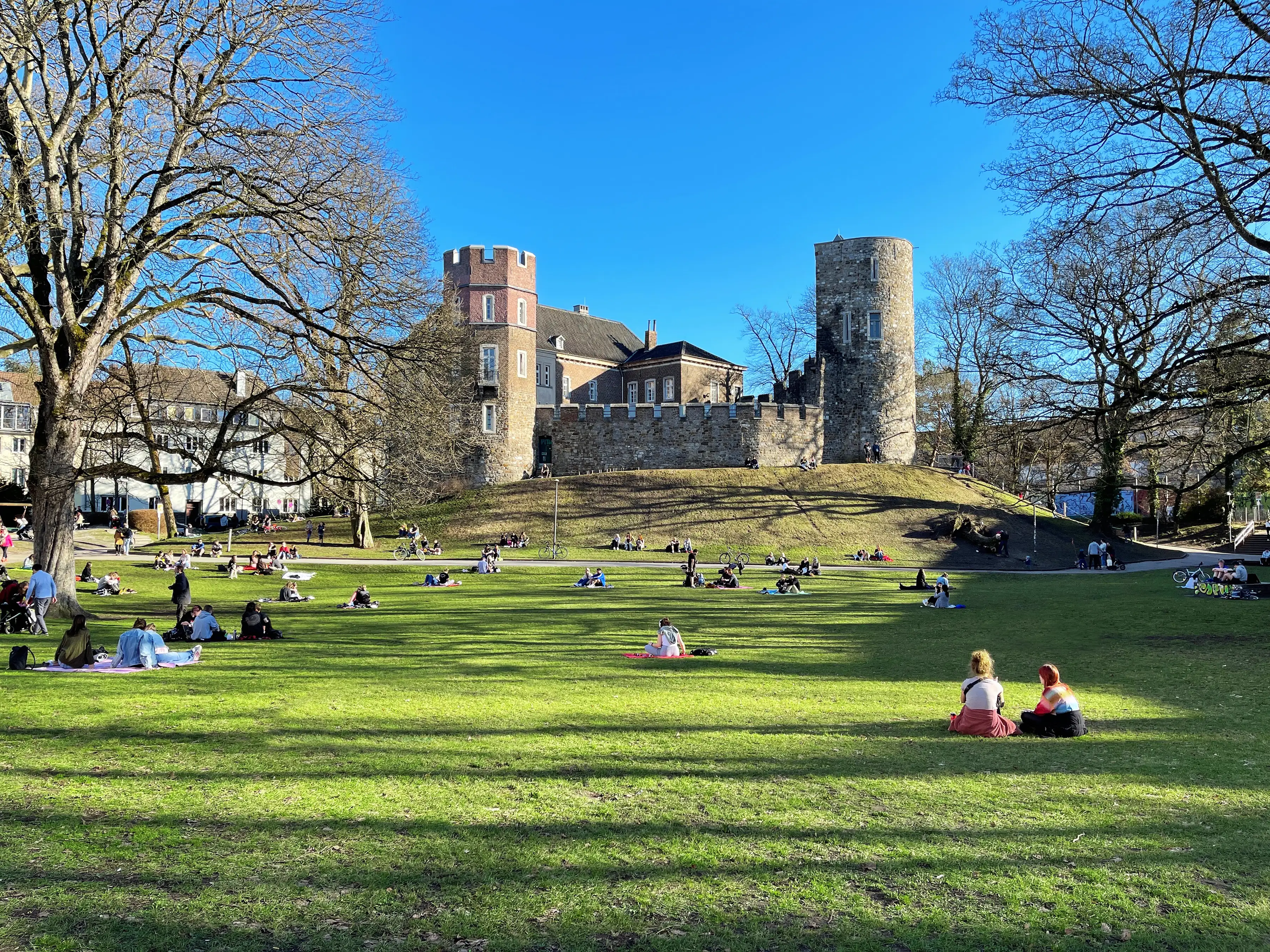 People sitting in an attractive park with a castle overlooking